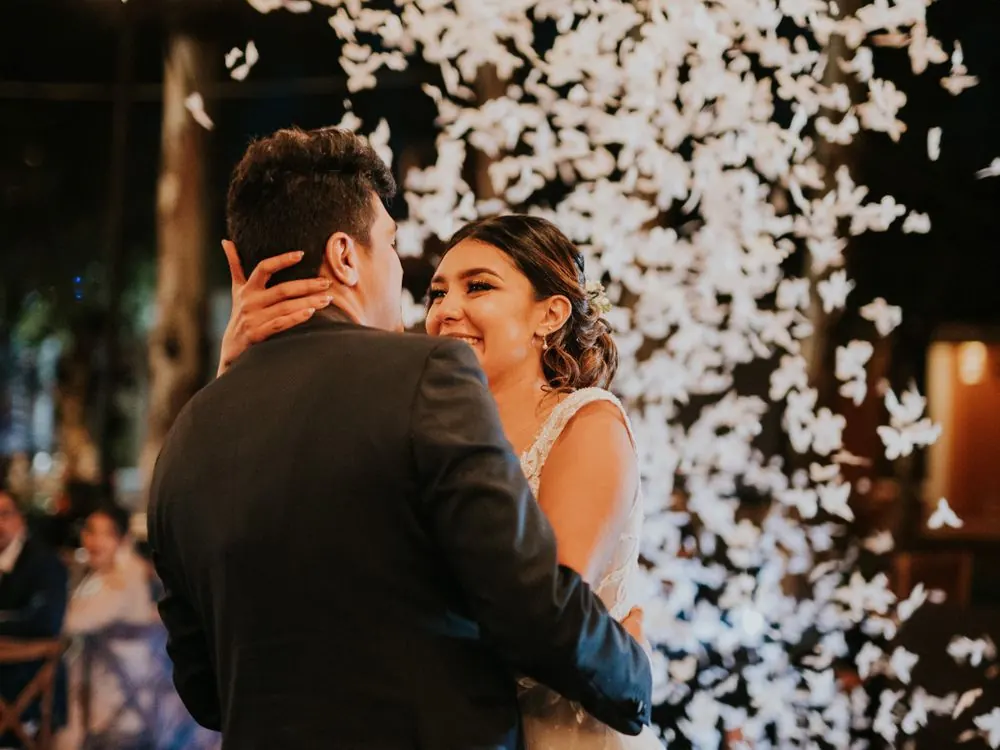 Noivos dançando sob chuva de pétalas na festa de casamento